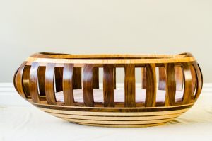 Walnut and maple egg-shaped cradle with bottom compartment